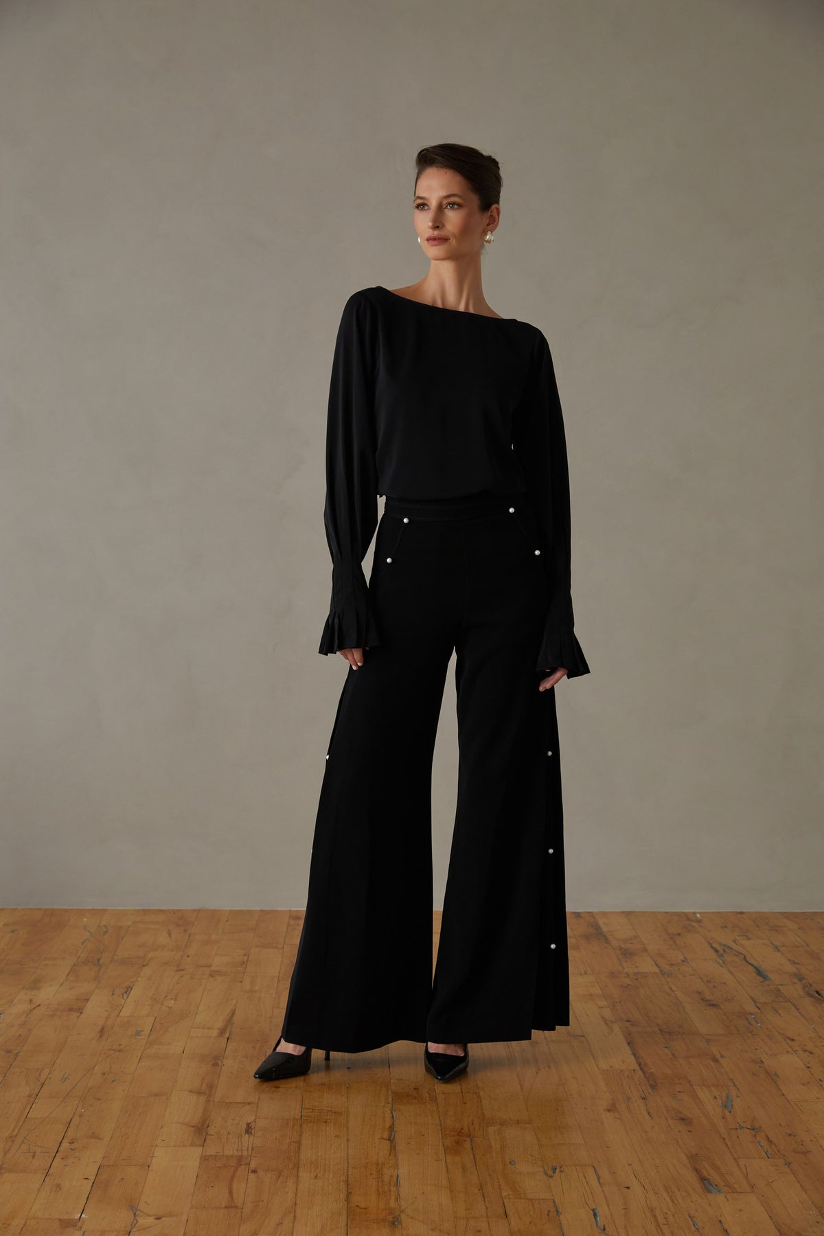 Simone pleated high-waisted trouser in black, worn with a black blouse